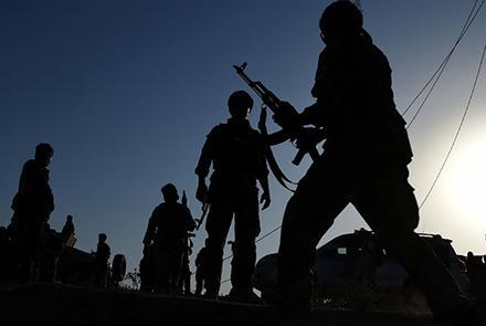 Silhouettes of armed men against a darkening sky
