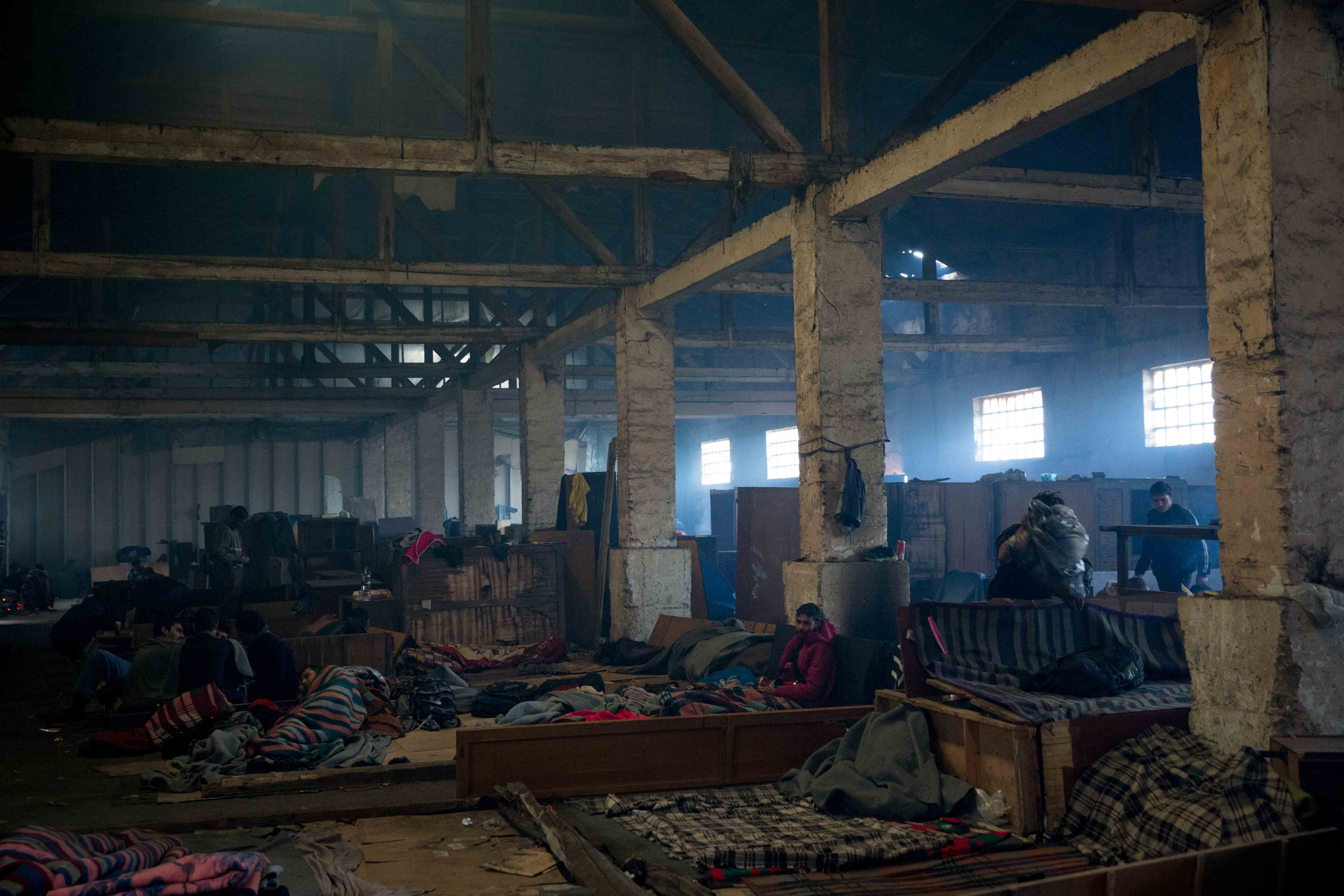 The main building is a large concrete shell with a leaking roof. The windows let in cold draughts, but not enough fresh air to counteract the thick smoke from the many small fires lit for cooking and to try to keep warm. The larger warehouses had been divided into makeshift ‘rooms’ often demarcated by wooden beams and derelict furniture. Photo: Martine van Bijlert