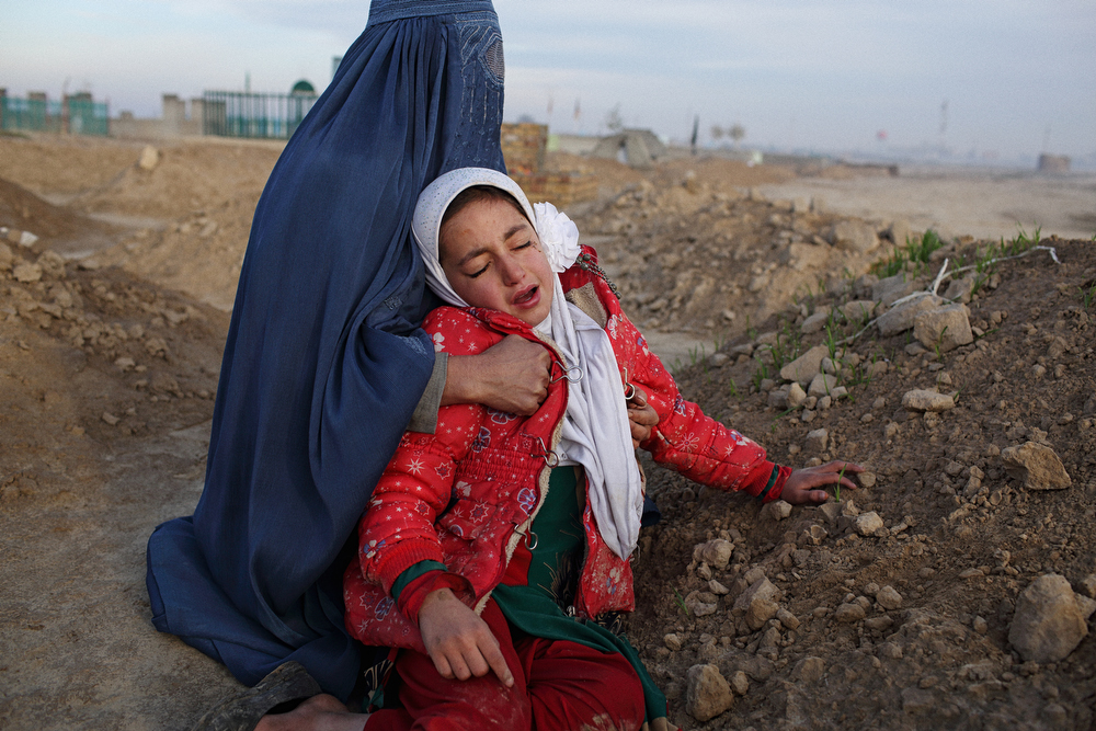 Najiba, the wife of Baynazar Mohammad Nazar who was killed when the MSF Kunduz Trauma Centre was destroyed by a US warplane, cradles her daughter Zahra as she cries over her father’s grave outside Kunduz City. “Father, we washed your bicycle – please wake up – you can come home now.” November 18, 2015.