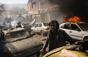 An injured man uses a piece of timber as a crutch to try to get away from the scene of one of the worst attacks since 2001. The Taleban said they were targeting the Ministry of Interior buildings in Kabul. Using a van painted to look like an ambulance, the suicide attack killed 114 civilians, and injured 229 more. Such intentional killing of civilians by Taleban is one of the crimes the ICC Prosecutor had wanted to investigate. (Photo: Andrew Quilty, 2018)